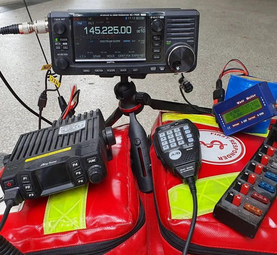 Mobile Funkausrüstung mit Transceiver, Mobilfunkgerät und Leistungsmesser auf roten Einsatztaschen